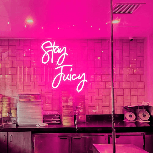 pink stay juicy neon sign on the wall